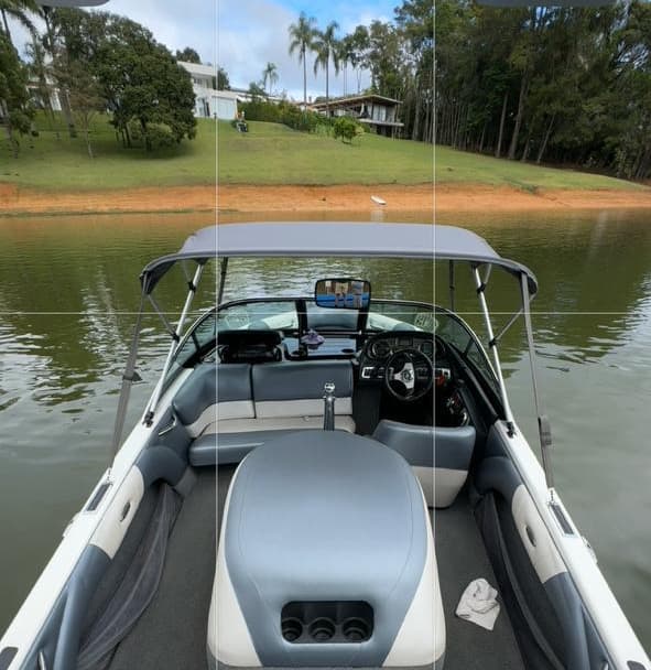 Interior de um Malibu visto da proa, com sofá em U, motor de centro e banco do piloto