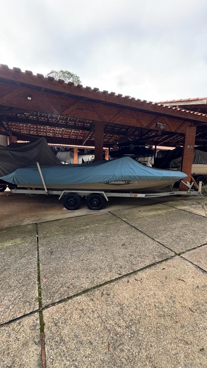 Barco de wake com a capa posta, guardado sob a garagem náutica